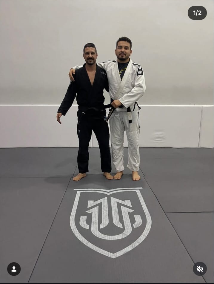 Instructor y alumno sobre el logo de University of Jiu-Jitsu